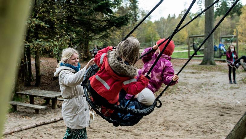 Kinder auf Schaukeln auf dem Waldspielplatz im Sønderskoven in Vejle