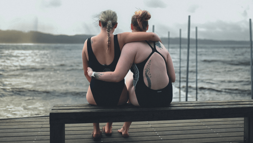 Zwei Frauen auf einer Bank gehen im Winter am Strand von Tirsbæk schwimmen