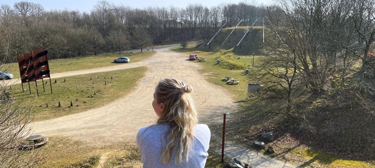 Eine Person macht eine Pause an der Kiesgrube Tørskind und genießt die Aussicht auf die Kiesgrube und die Skulptur