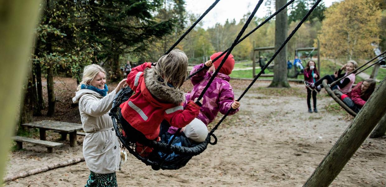 Kinder auf Schaukeln auf dem Waldspielplatz im Sønderskoven in Vejle