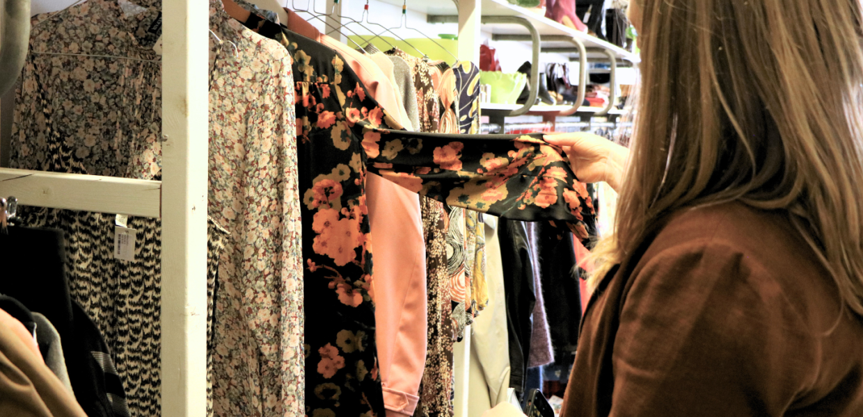 Eine Person schaut sich Kleidung in einem Secondhand-Laden in Give an