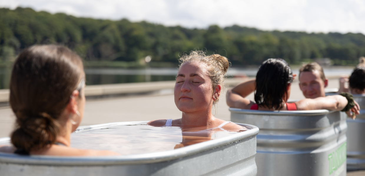 Frauen sitzen nach dem Saunagus mit dem Saunatruck in Vejle am Hafen in einem Badezuber.
