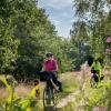 Radfahrer auf dem Hærvejen an der Quelle des Gudenåen mit Blumen im Vordergrund