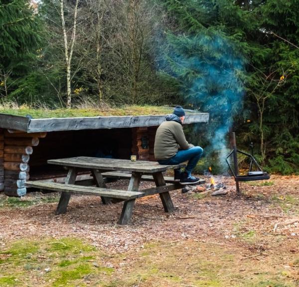 Eine Person ist auf einem Shelterausflug in Frederikshåb Plantage und macht ein Feuer