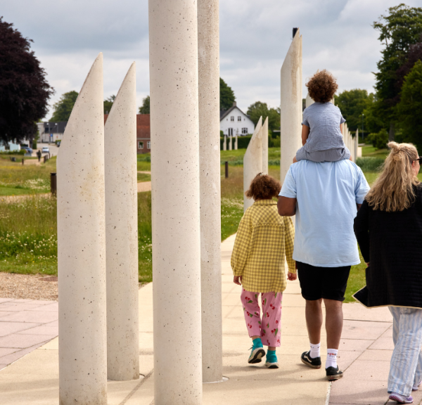 Eine Familie spaziert im Monumentbereich in Jelling bei den Palisaden