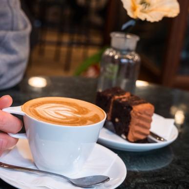 Eine Person sitzt im Café Conrads und holt sich Kaffee und Kuchen