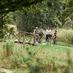 Familie mit zwei Erwachsenen und drei Kindern radelt entlang des Bindeballestien in der Nähe von Vingsted