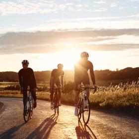 Cyklister på cykeltur ved Jelling med solnedgang