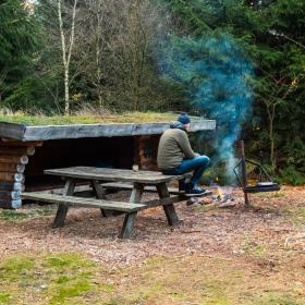 Eine Person ist auf einem Shelterausflug in Frederikshåb Plantage und macht ein Feuer