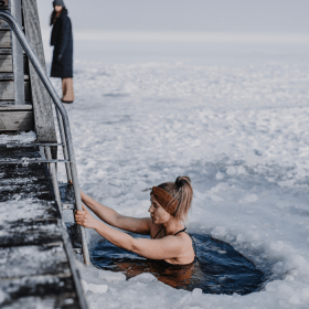 Frau badet im Winter am Fjord mit Eis auf dem Fjord