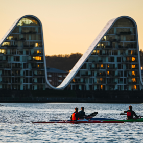 Menschen in Kajaks auf dem Vejle-Fjord mit Bølgen (der Welle) im Hintergrund