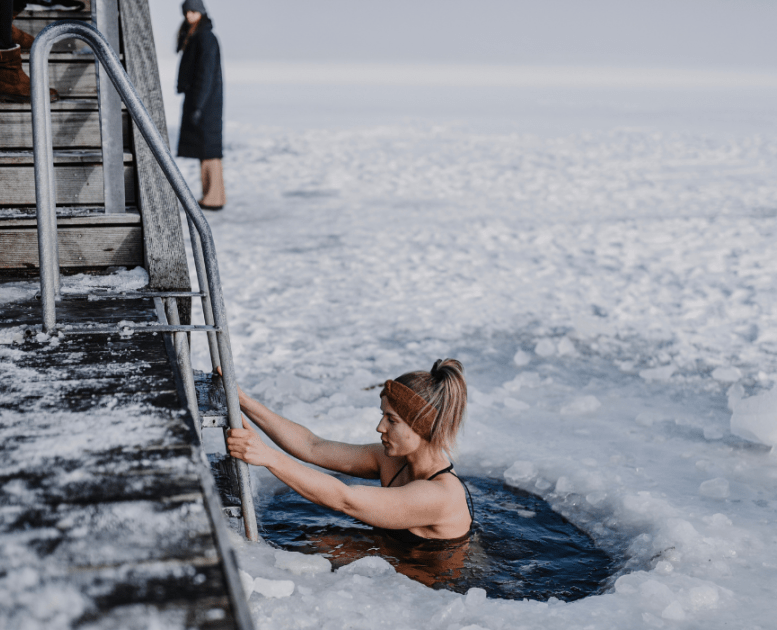 Frau badet im Winter am Fjord mit Eis auf dem Fjord
