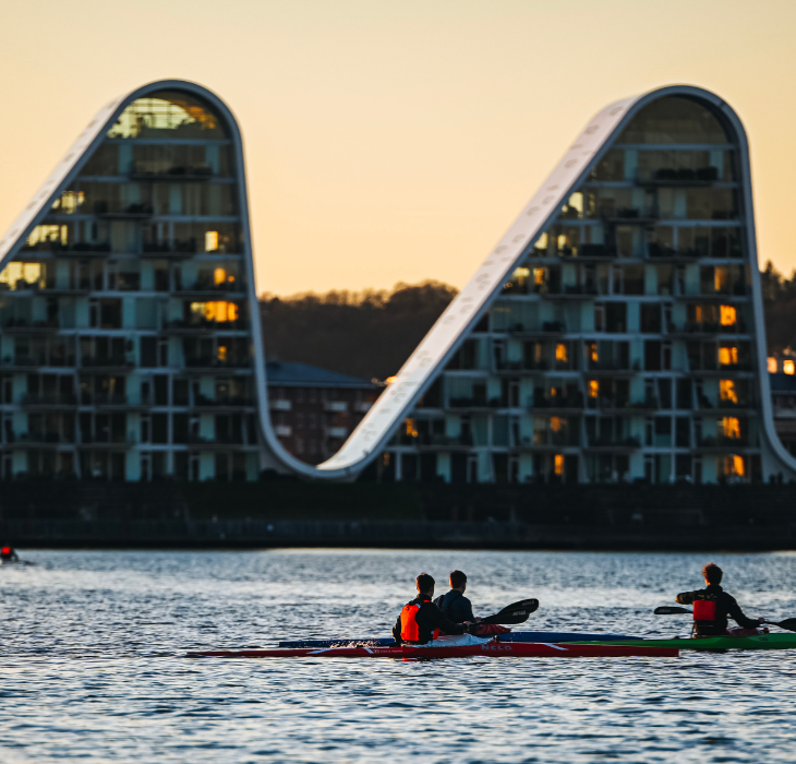 Menschen in Kajaks auf dem Vejle-Fjord mit Bølgen (der Welle) im Hintergrund